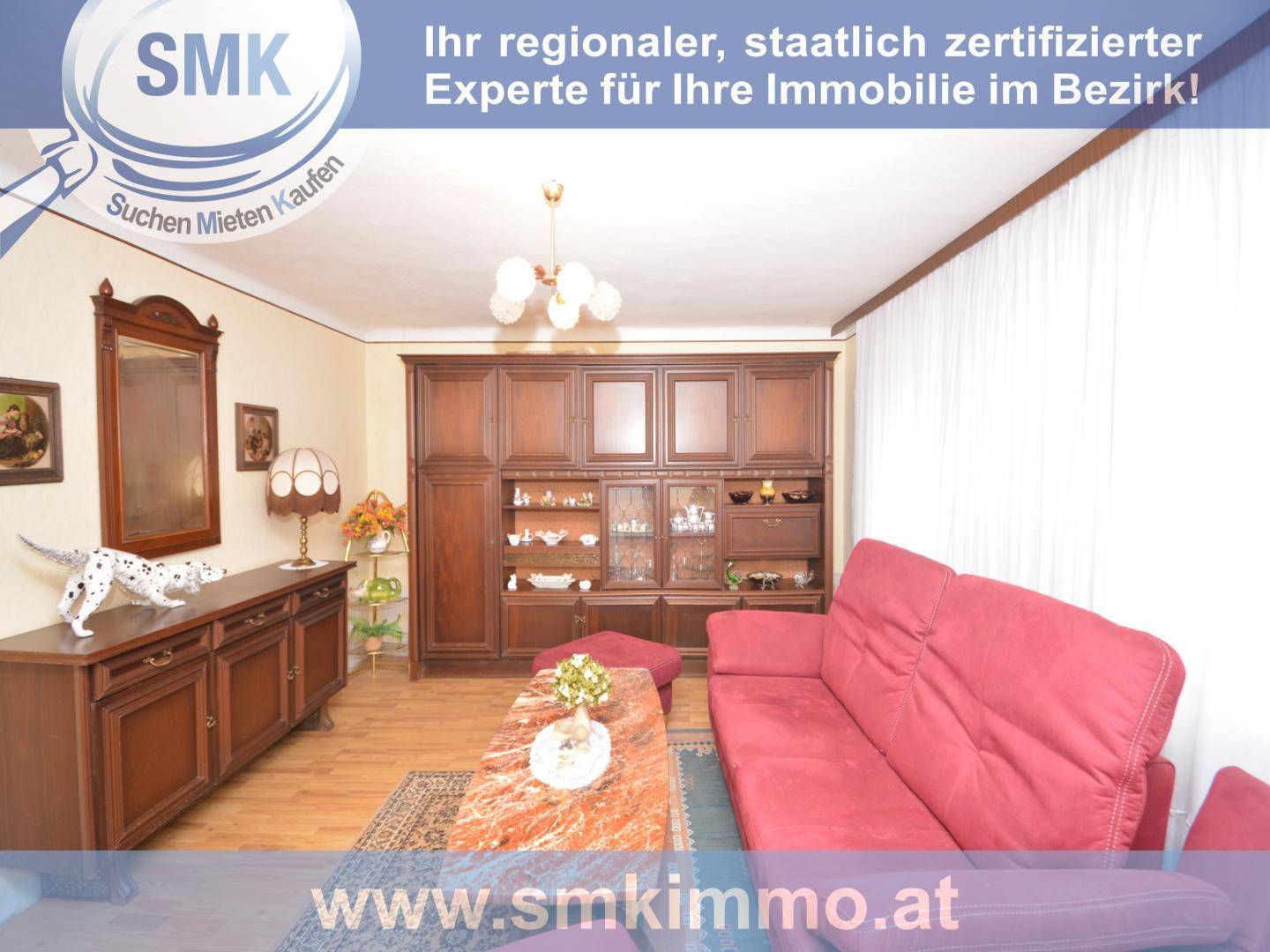 Geräumiges Wohnzimmer mit rotem Sofa und großem Holzschrank.