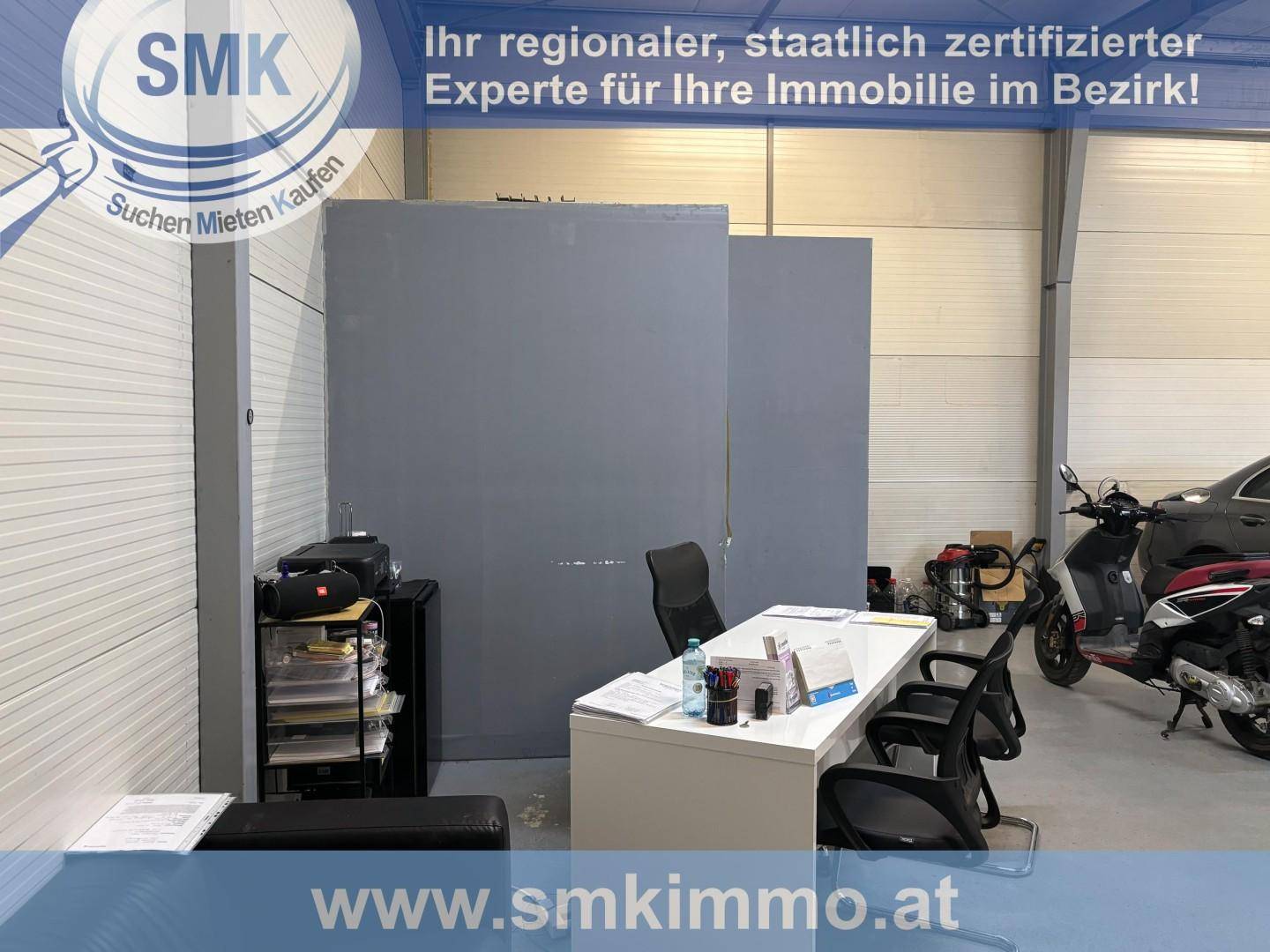 Bürobereich innerhalb einer Gewerbeeinheit mit Schreibtisch, Stühlen und Motorrädern im hinteren Teil des Raumes.
