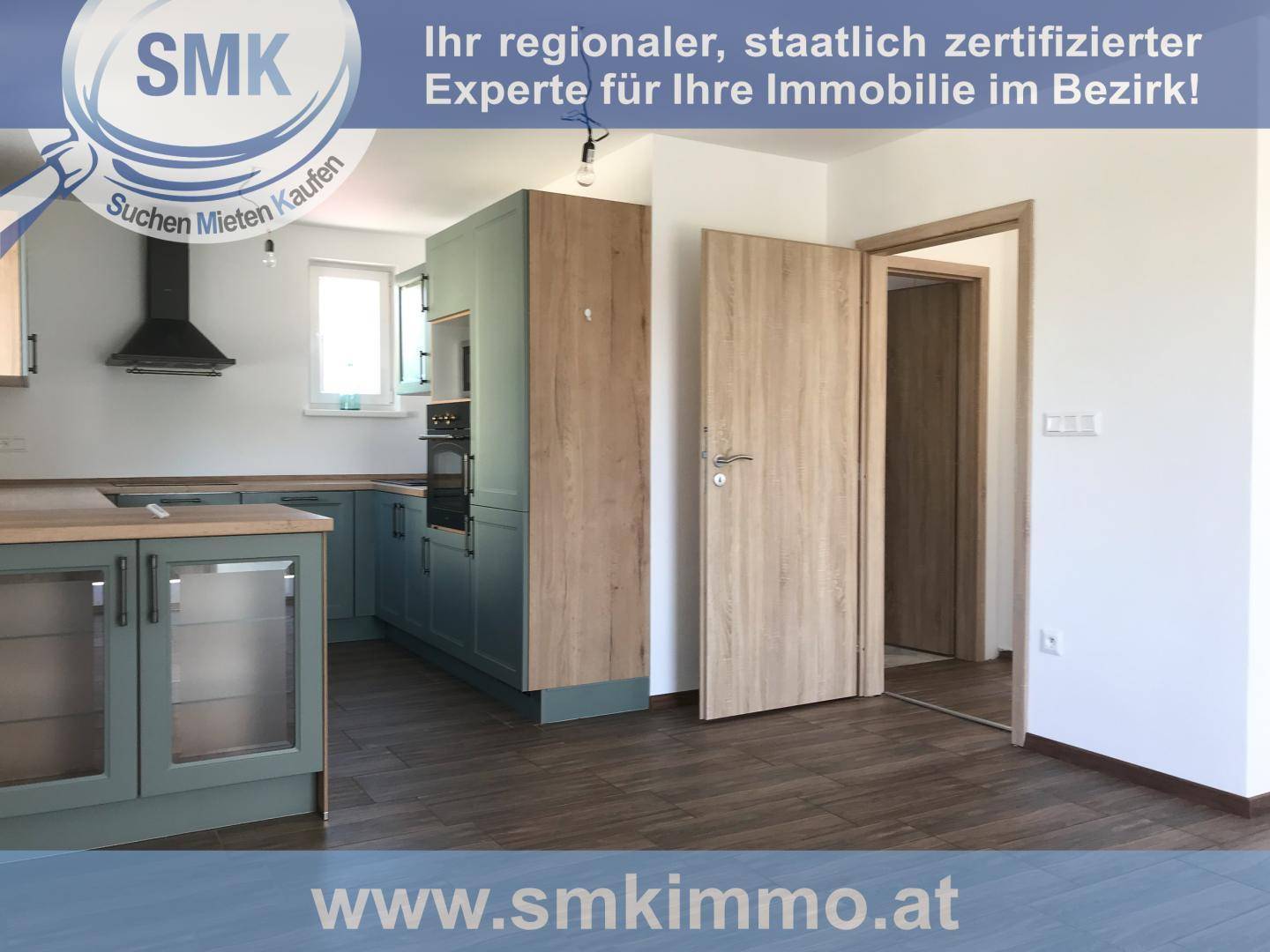 Offene Küche mit grünen Schränken, Dunstabzugshaube und Zugang zu einem weiteren Raum, mit Fliesenboden.