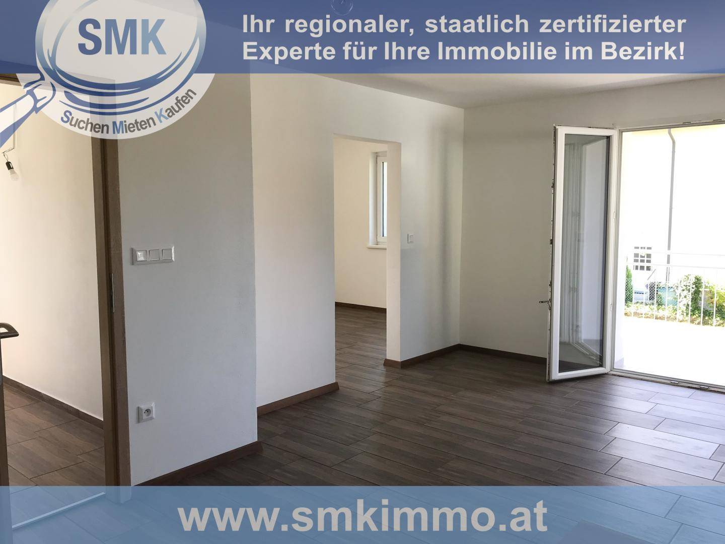 Geräumiger, heller Innenraum mit dunklem Fliesenboden und Zugang zu weiteren Zimmern, unmöbliert.
