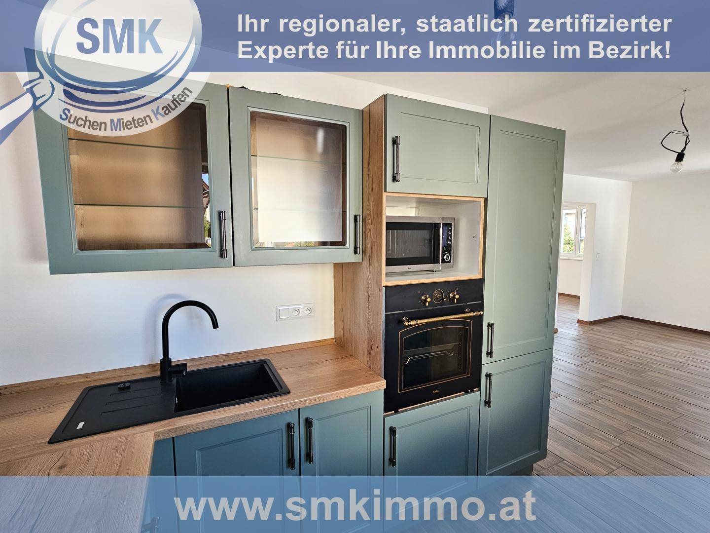 Moderne Einbauküche mit grünen Schränken, Holzarbeitsplatte und integrierten Geräten wie Backofen und Mikrowelle.