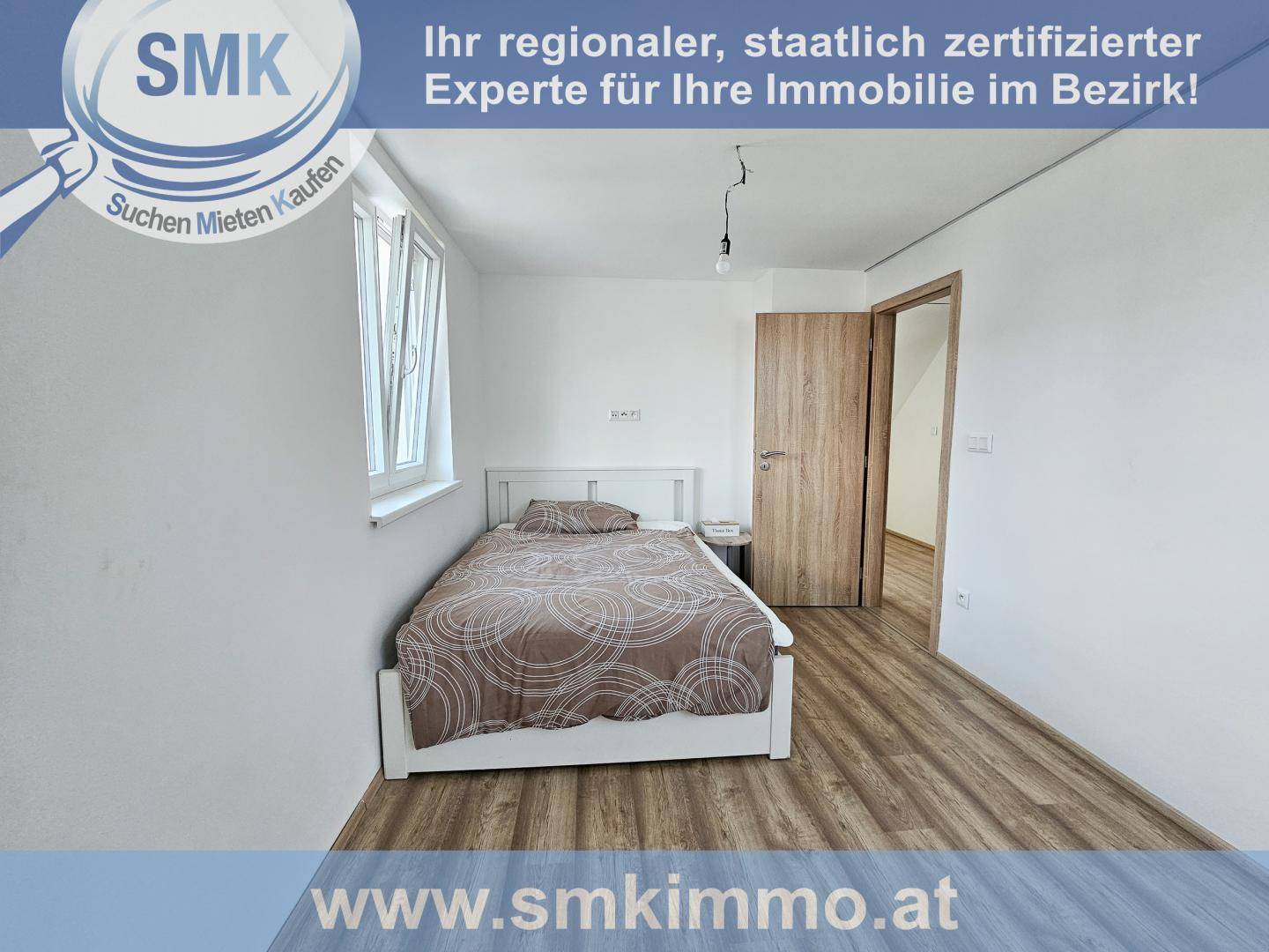 Helles Schlafzimmer mit Einzelbett, Laminatboden und einem Fenster mit Blick nach draußen.