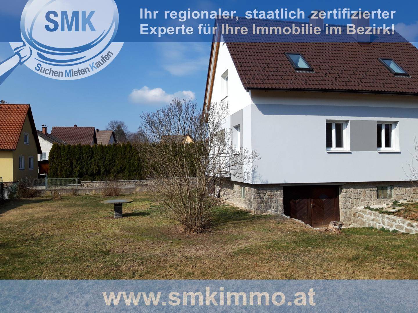 Einfamilienhaus mit Gartenbereich und Kellerzugang, umgeben von einer ländlichen Umgebung und Bäumen.