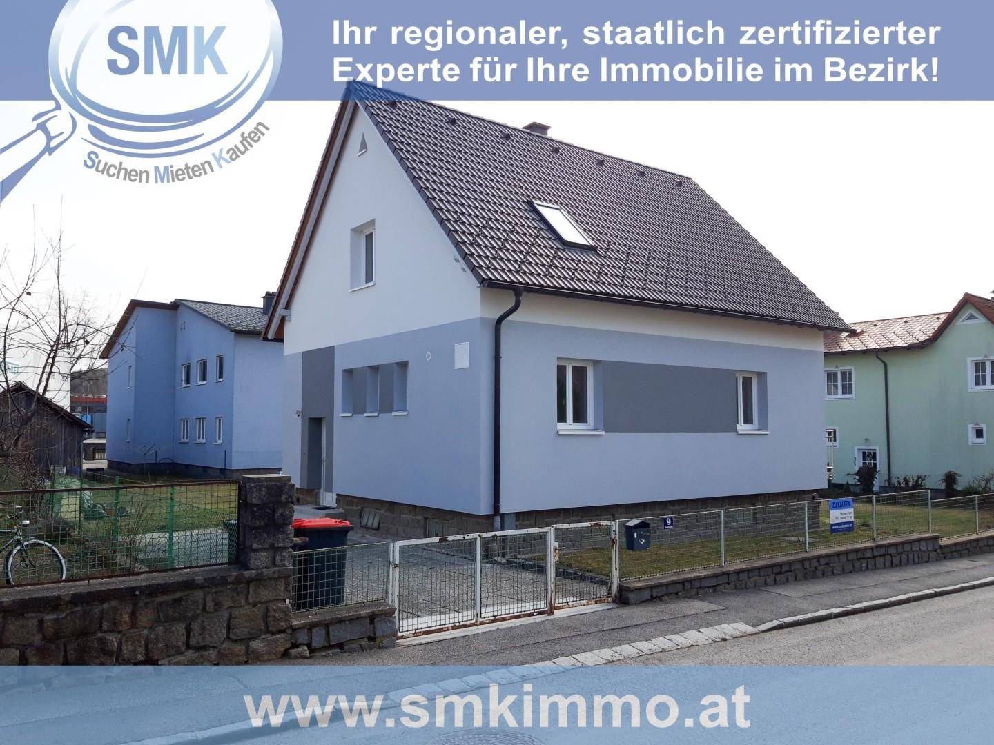 Ansicht eines Einfamilienhauses von der Straße mit hellblauer Fassade und braunem Ziegeldach.