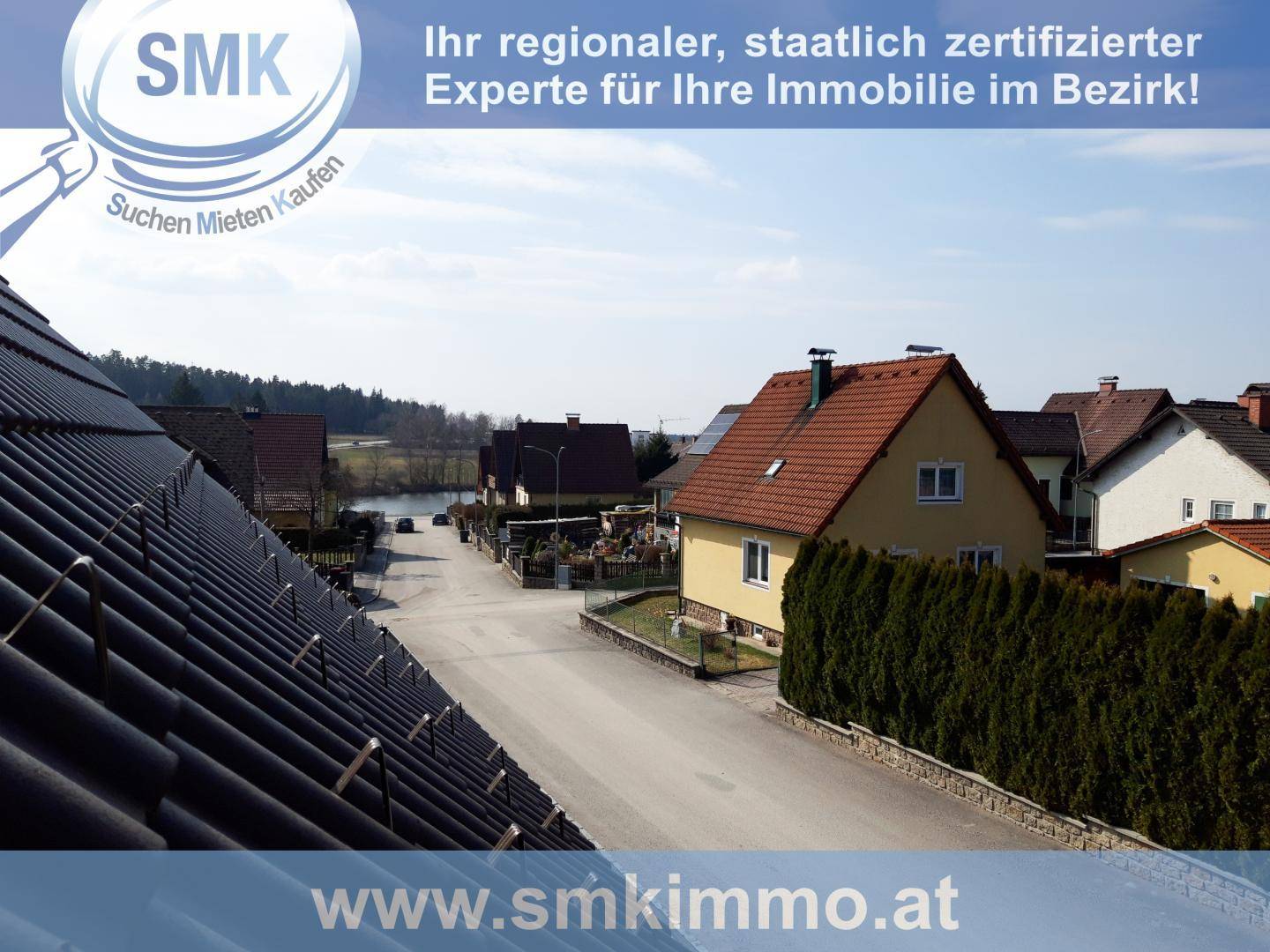 Luftaufnahme einer Wohnsiedlung mit Einfamilienhäusern und grüner Umgebung unter blauem Himmel.