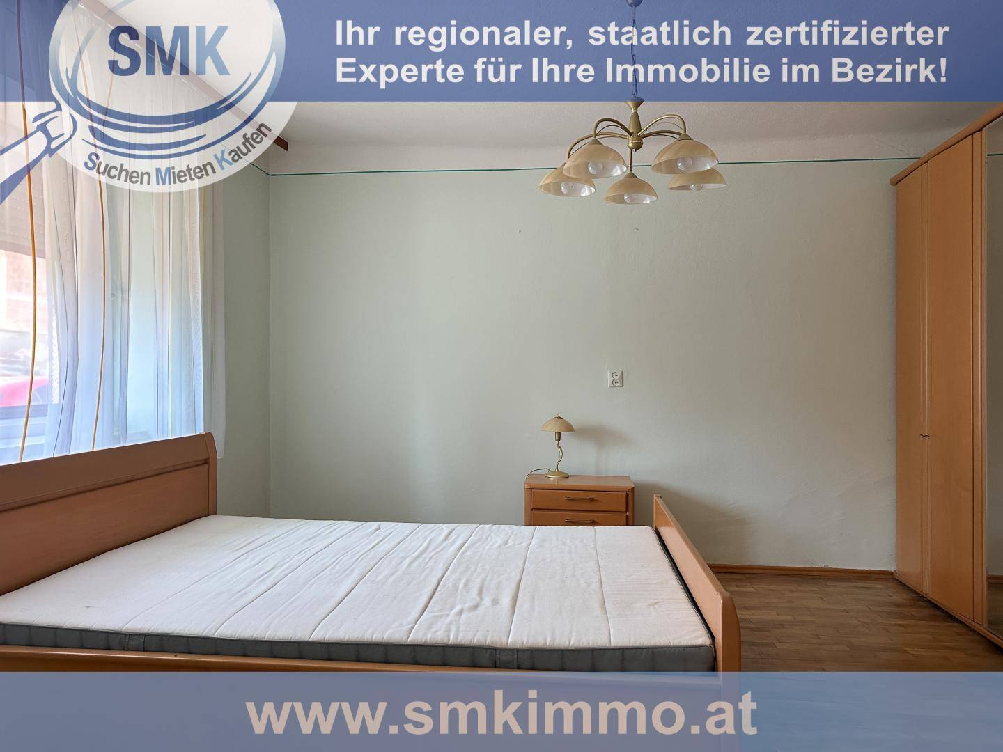 Schlafzimmer mit Doppelbett, Nachttisch und Kleiderschrank, hell gestrichene Wände.