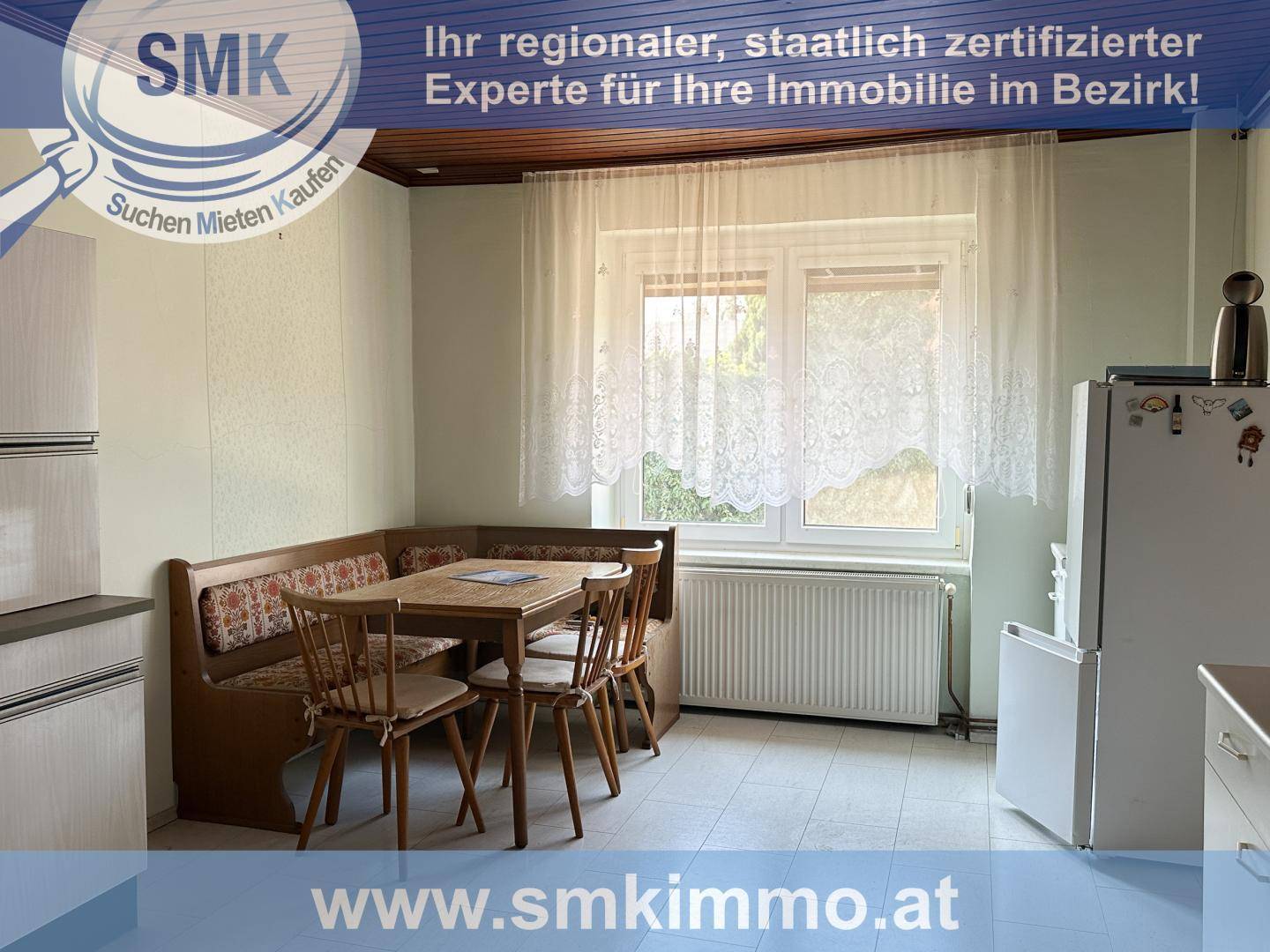 Gemütliche Küche mit Essbereich, Holzdecke und Blick ins Grüne durch das Fenster.
