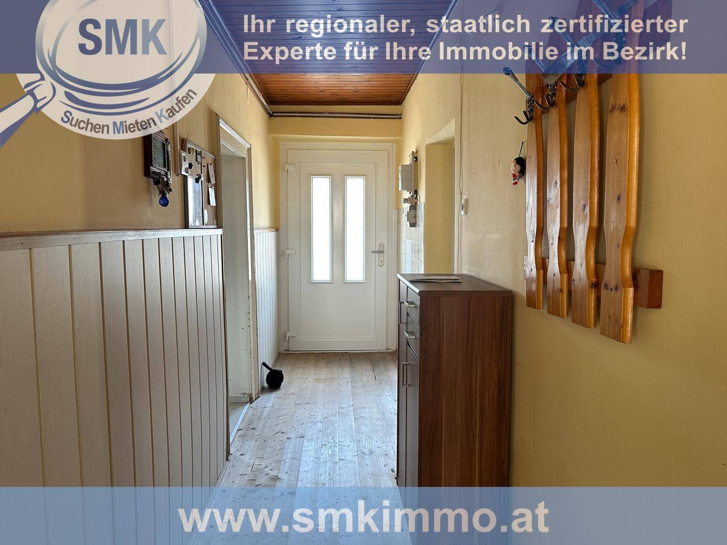 Eingangsbereich mit Holzboden, Garderobe und Holztäfelung an den Wänden.