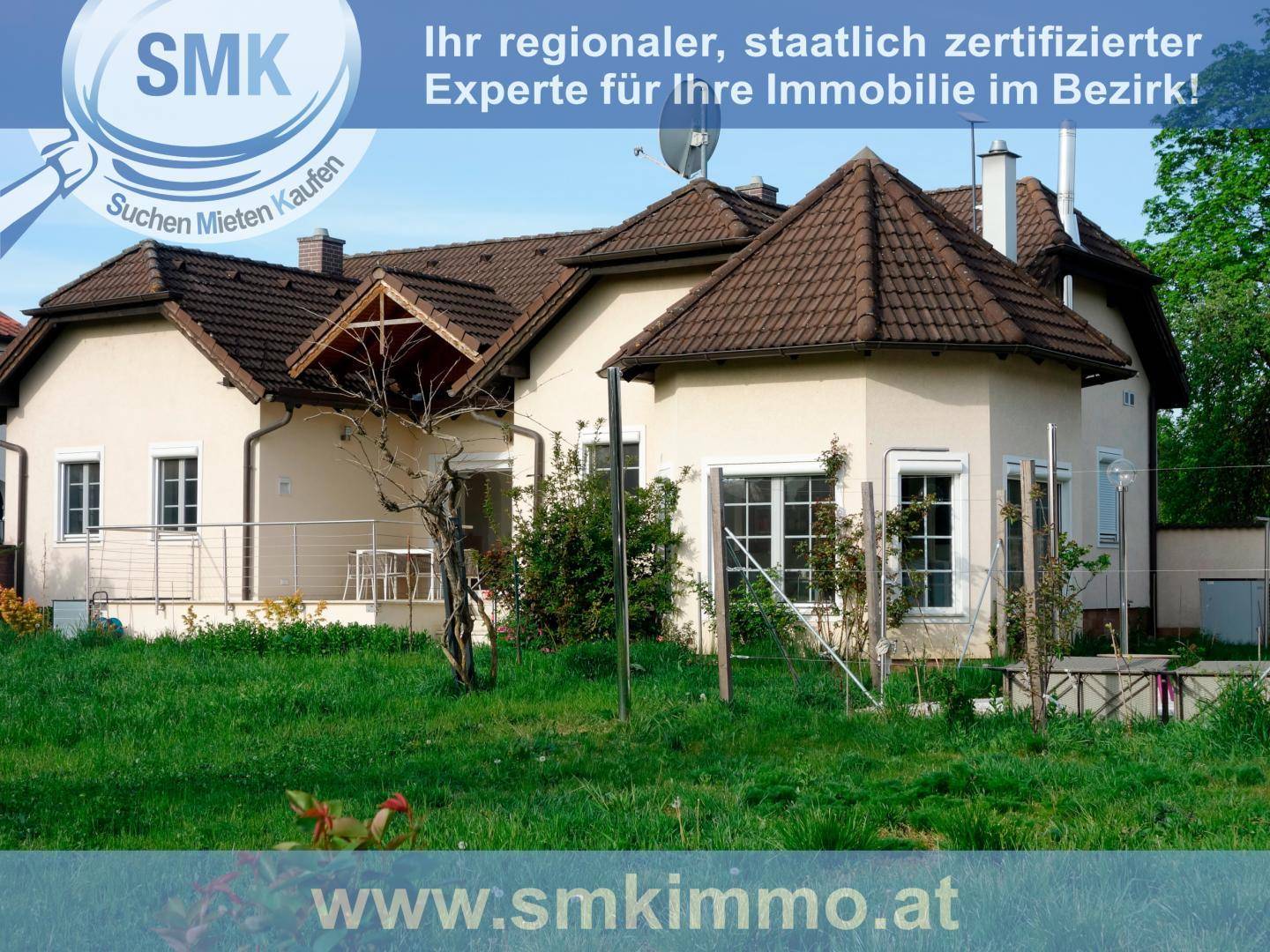 Ansicht eines Einfamilienhauses mit heller Fassade, Ziegeldach und gepflegtem Rasen.