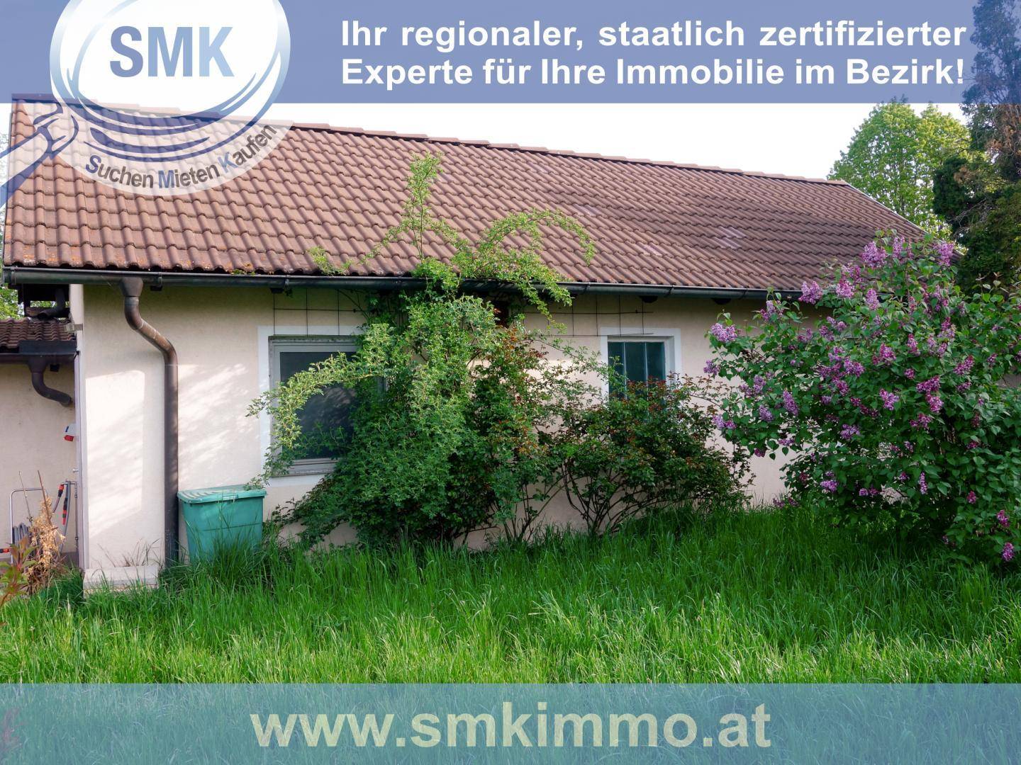 Seitenansicht des Hauses mit üppiger Vegetation und blühenden Sträuchern im Garten.