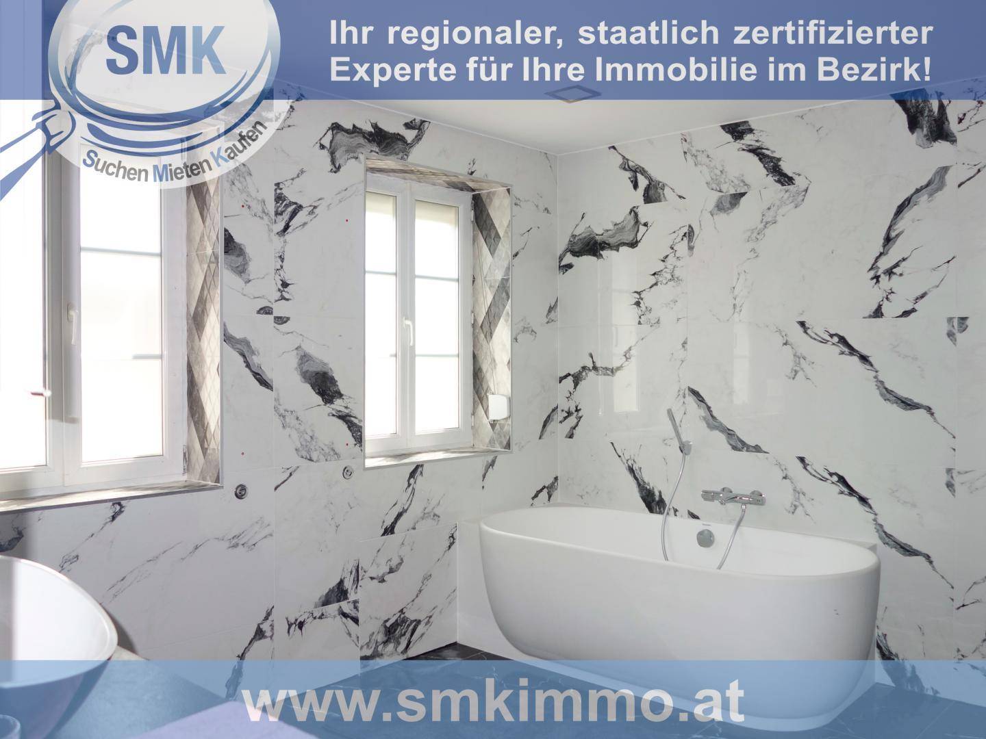 Modernes Badezimmer mit freistehender Badewanne und auffälligen Marmor-Effekt-Fliesen an den Wänden.