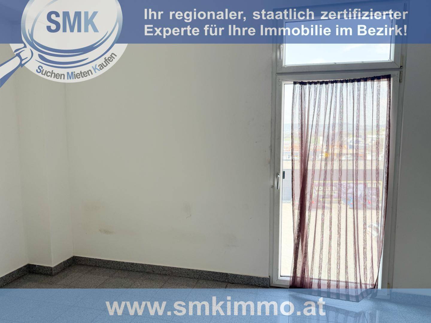 Heller Raum mit weiß gestrichenen Wänden, Fliesenboden und einem großen Fenster mit Vorhang.