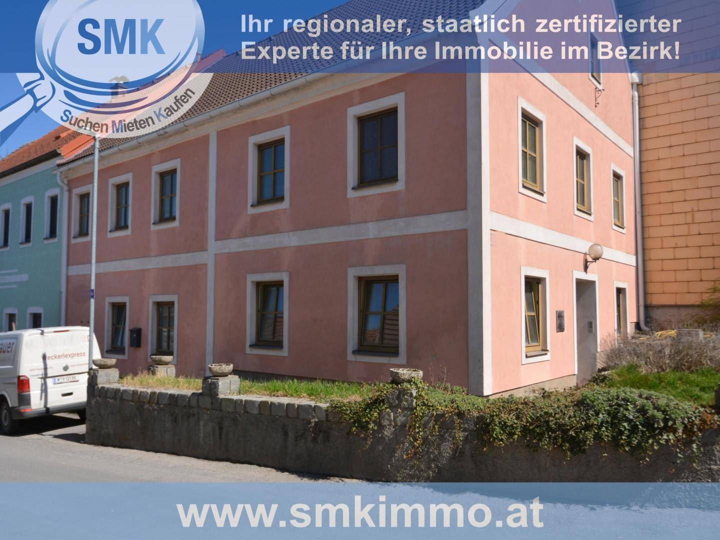 Ansicht der rosa gestrichenen Hausfassade mit mehreren Fenstern und einem Lieferwagen davor.