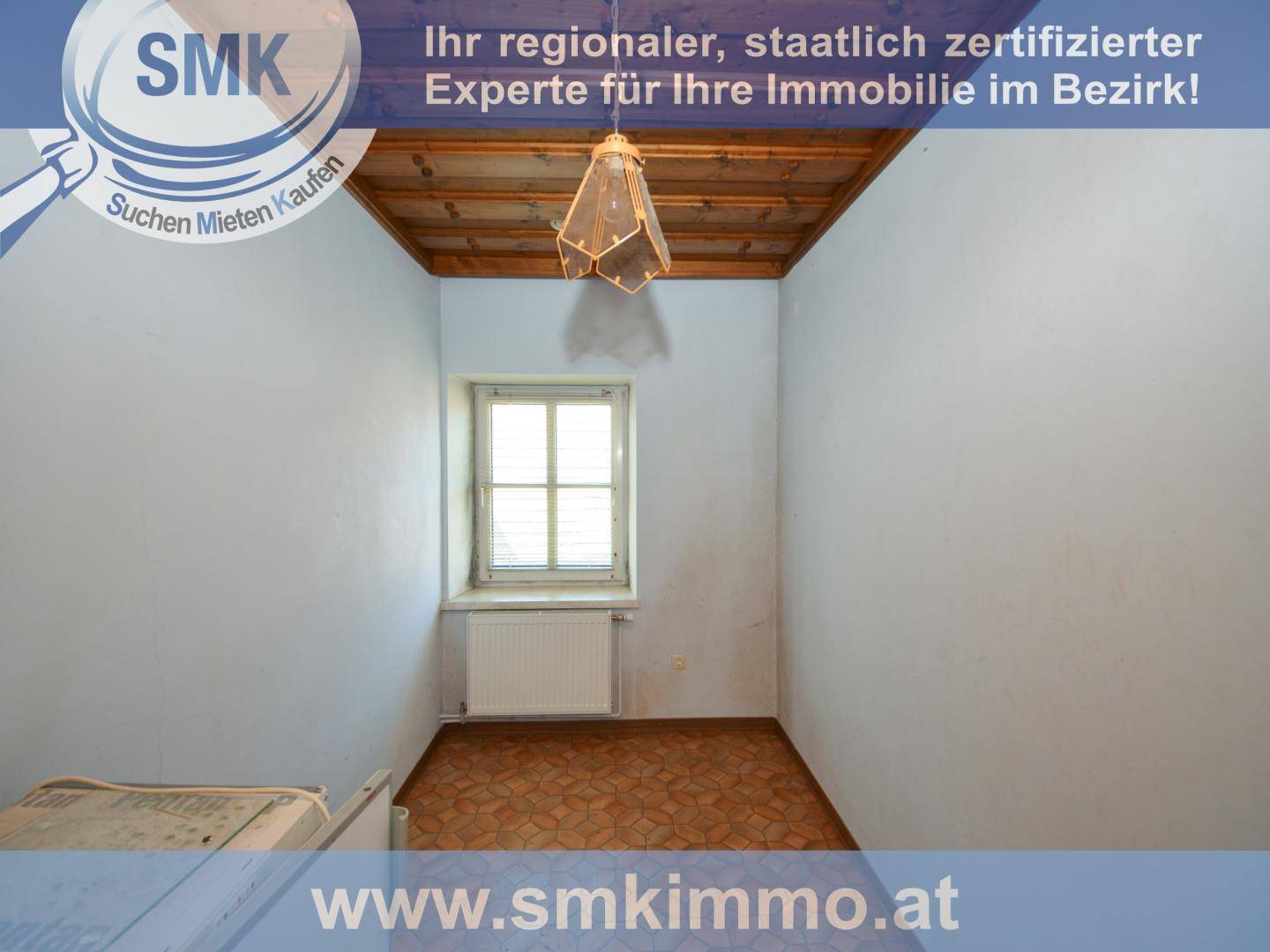 Kleines Zimmer mit Holzbalkendecke, Parkettboden und einem Fenster mit Heizkörper.