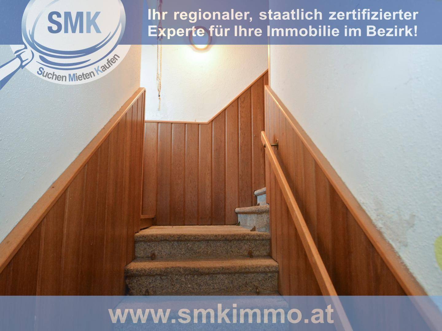 Holzvertäfelte Treppe mit Teppichstufen, die in ein oberes Stockwerk führt.