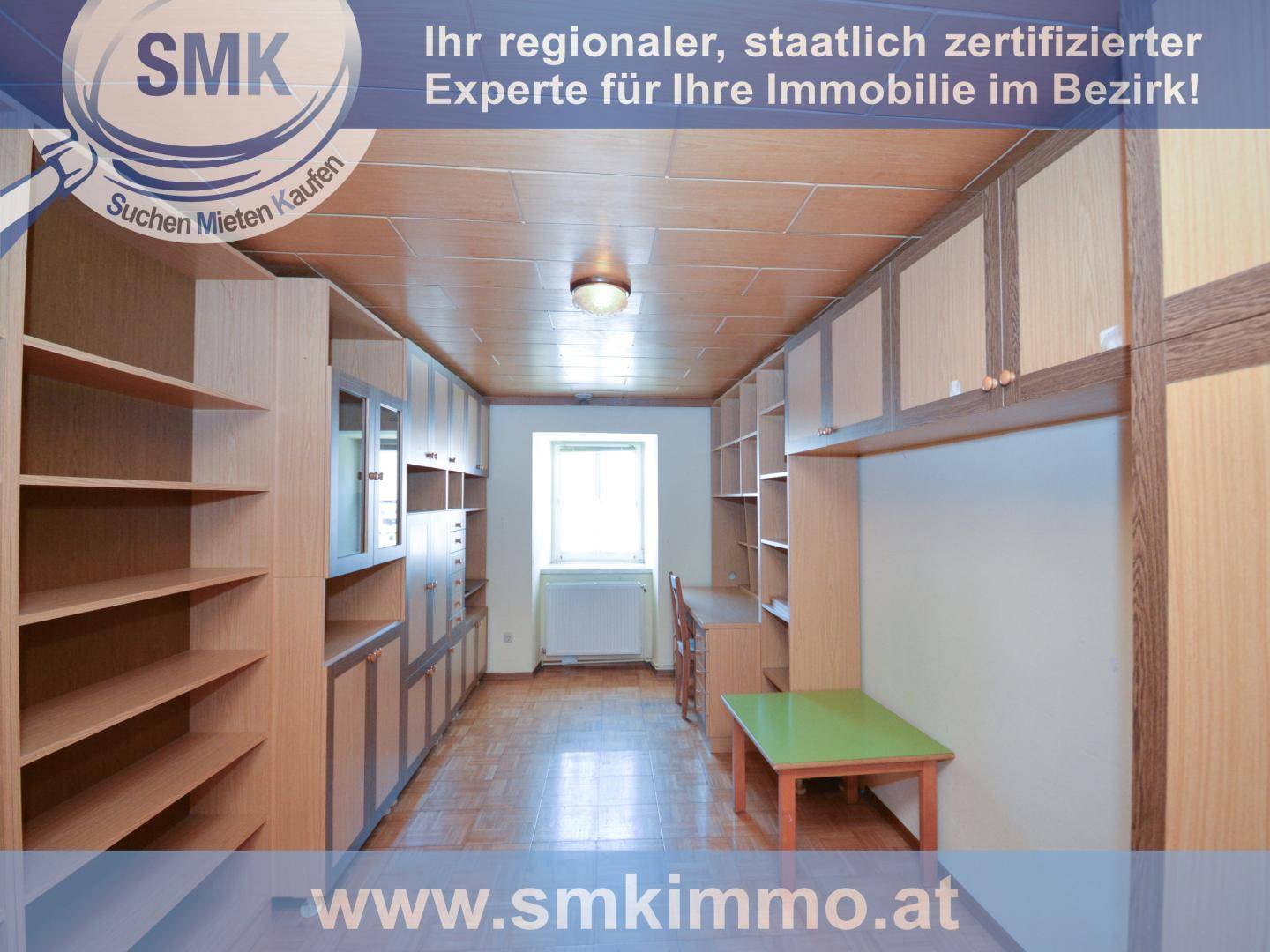 Arbeitszimmer mit vielen eingebauten Holzregalen, Parkettboden und einem Fenster.