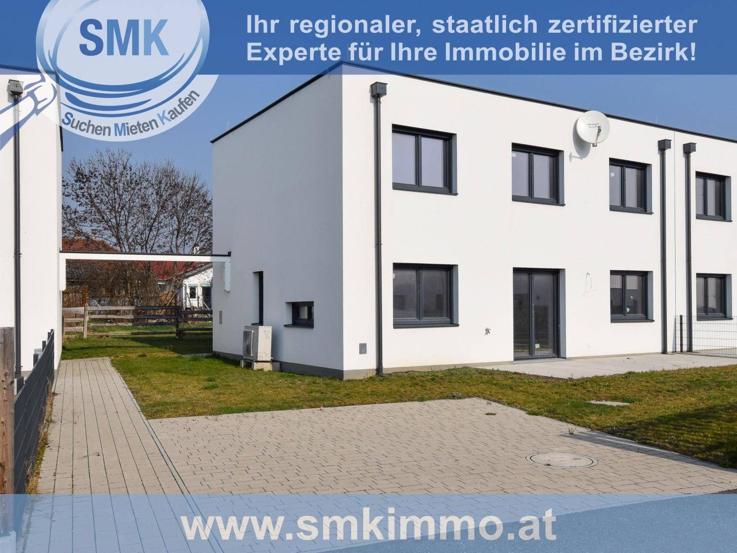 Moderne weiße Reihenhäuser mit gepflegtem Rasen und gepflastertem Zugangsbereich.