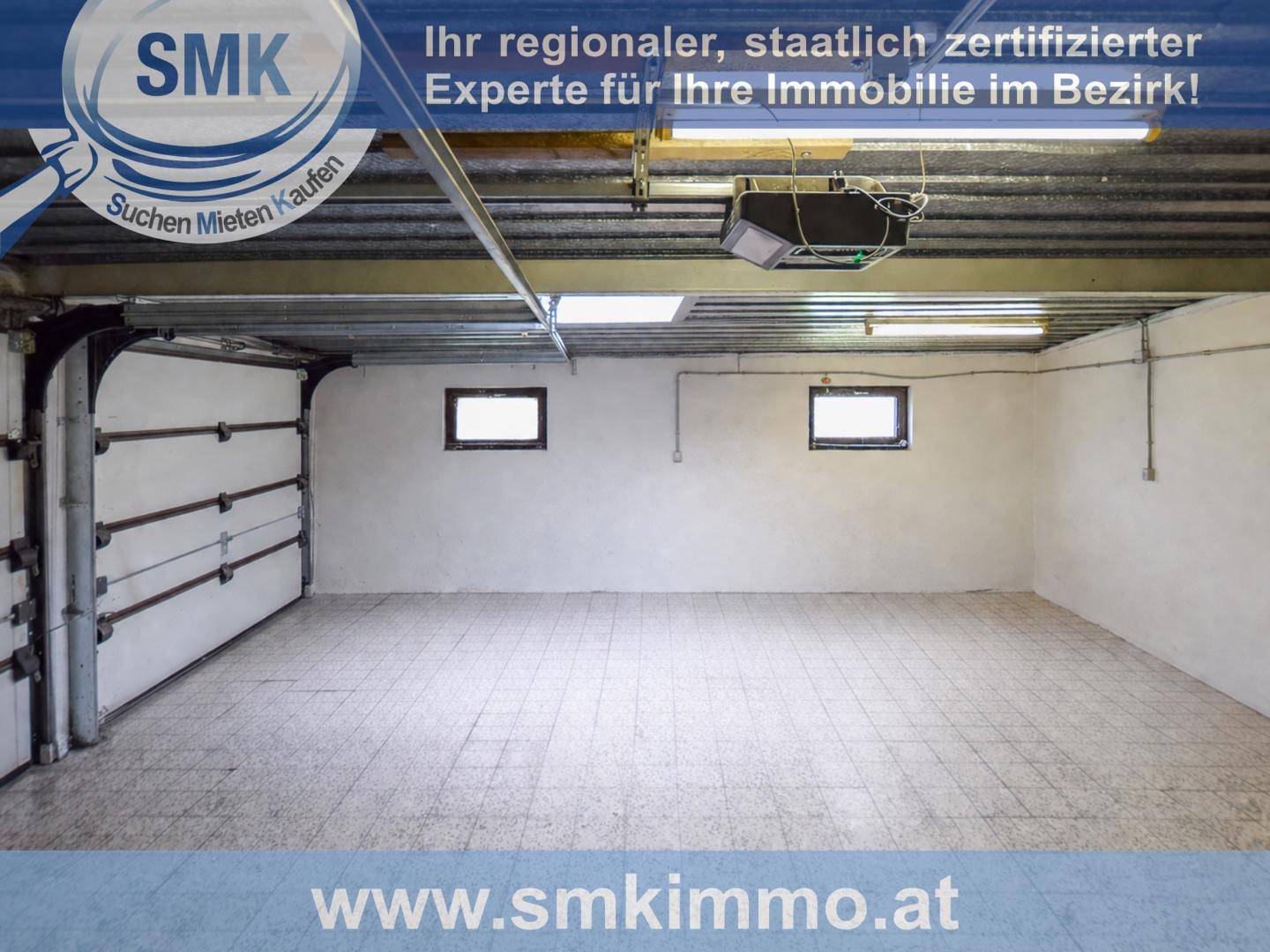 Geräumige Garage mit zwei Toren und Fliesenboden, bietet Platz für mehrere Fahrzeuge.