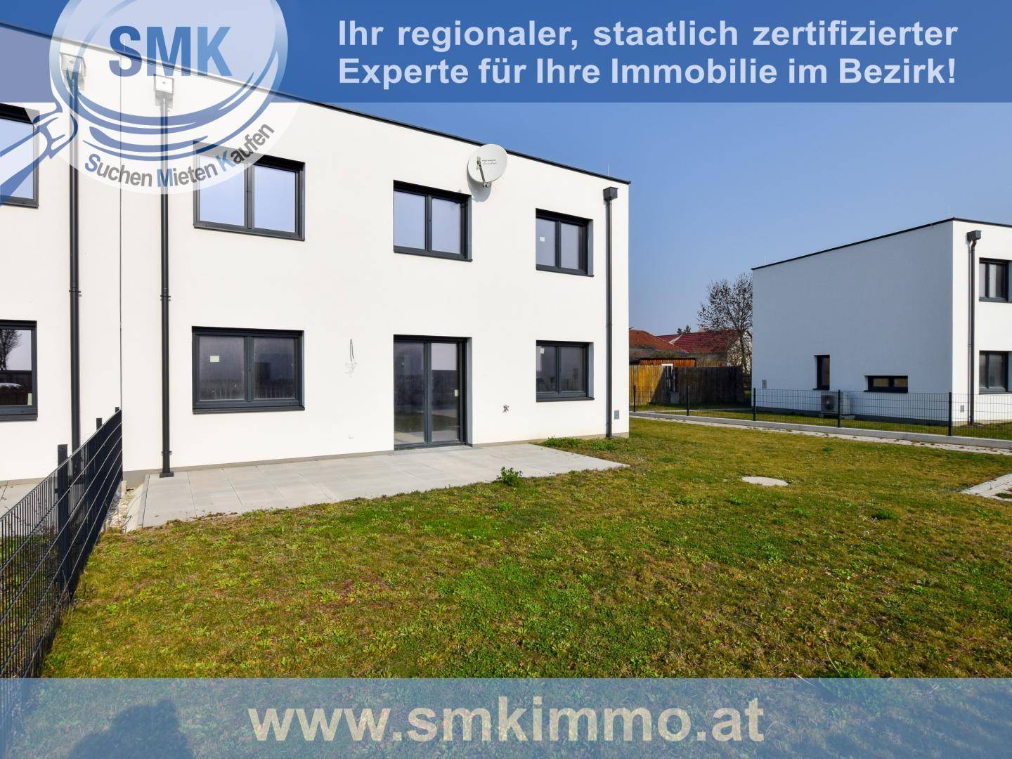 Moderner Neubau mit kleiner Terrasse und Rasenfläche, umgeben von weiteren neuen Häusern.