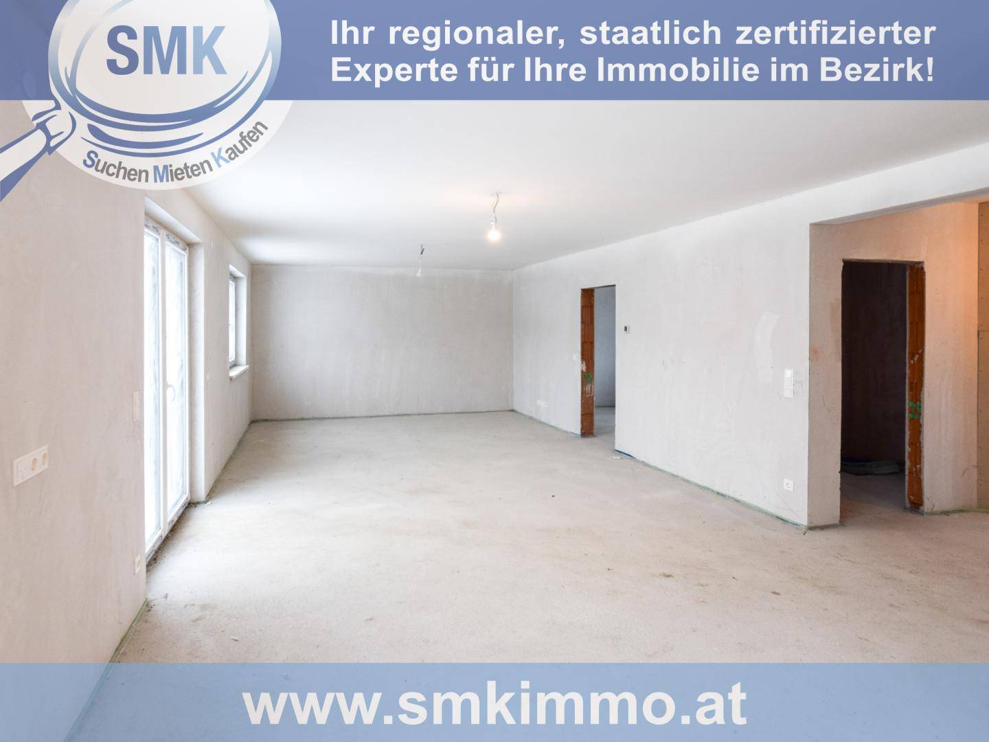 Unfertiger Innenraum mit Rohbauwänden, Betonboden und Zugang zum Außenbereich.