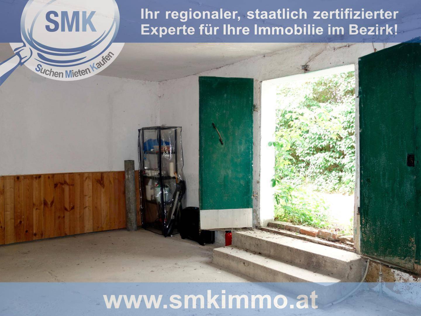 Einfacher Innenraum, möglicherweise eine Garage oder Abstellraum, mit Betonboden und Holzwänden.