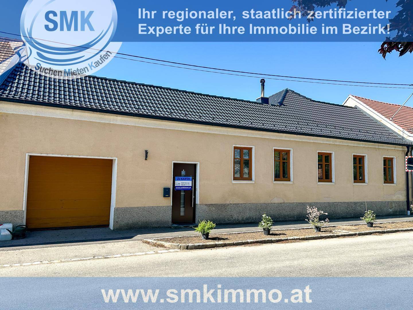 Straßenansicht der Hausfassade mit Garage und mehreren Fenstern.