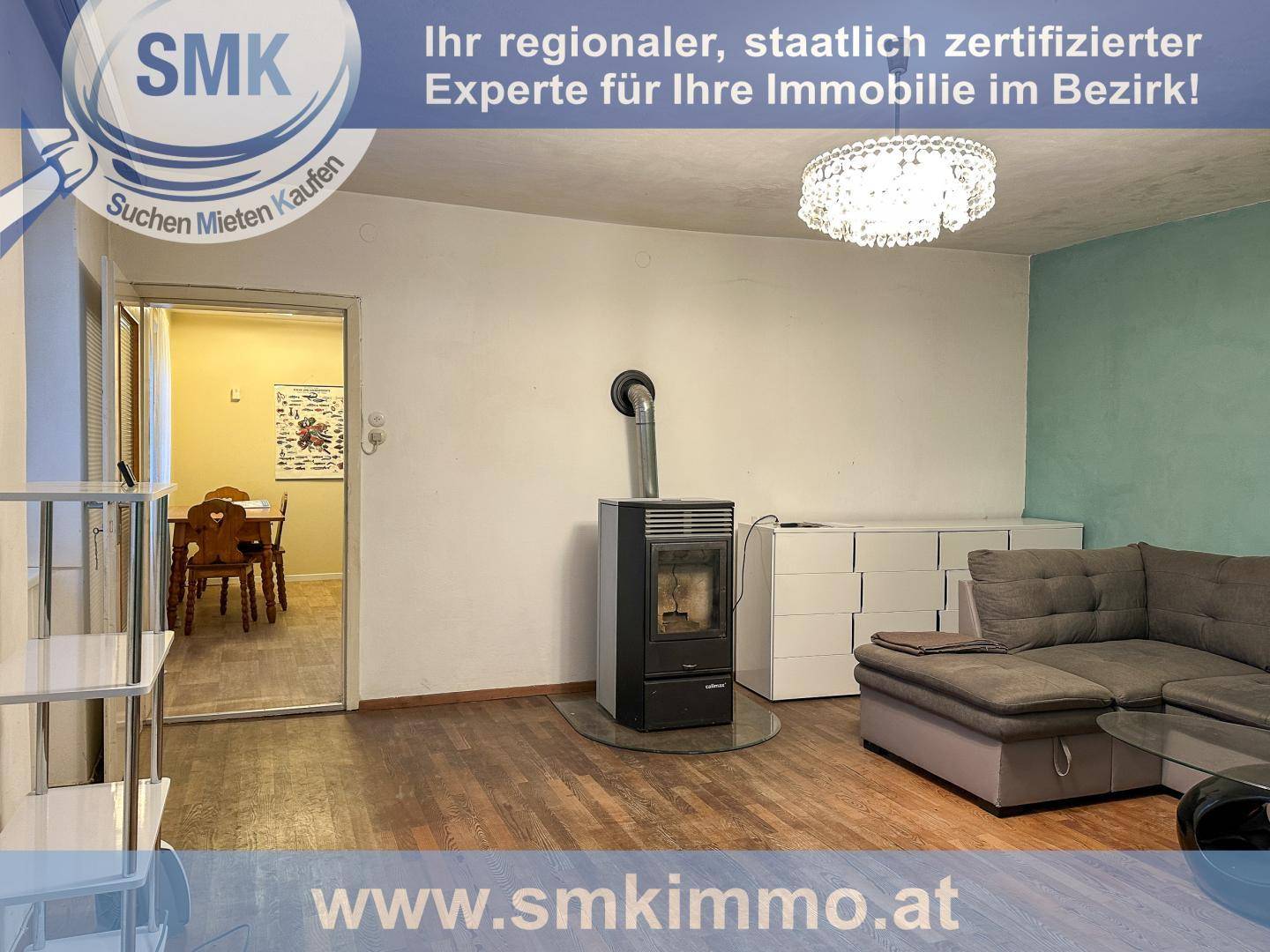 Gemütliches Wohnzimmer mit modernem Holzofen, Sofa und Kronleuchter.