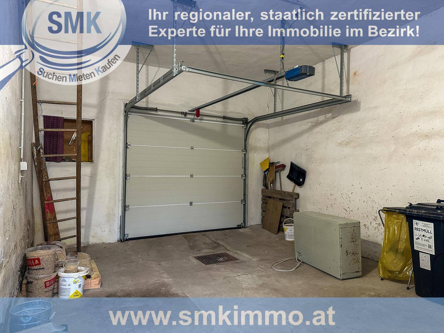 Geräumige Garage mit Rolltor, Betonboden und Stauraum für Werkzeuge.