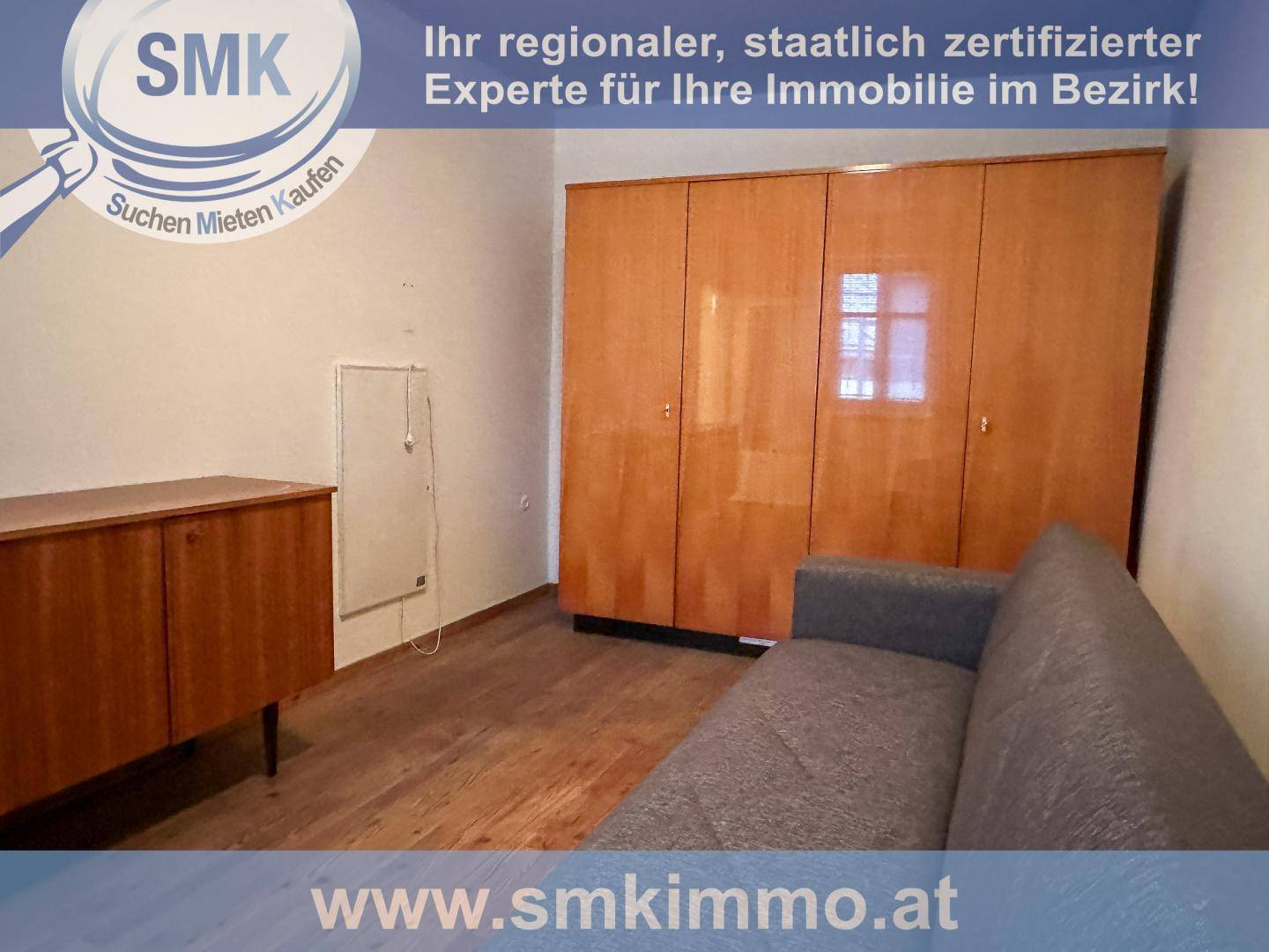 Schlafzimmer oder Mehrzweckraum mit großem Holzschrank und Sofa.