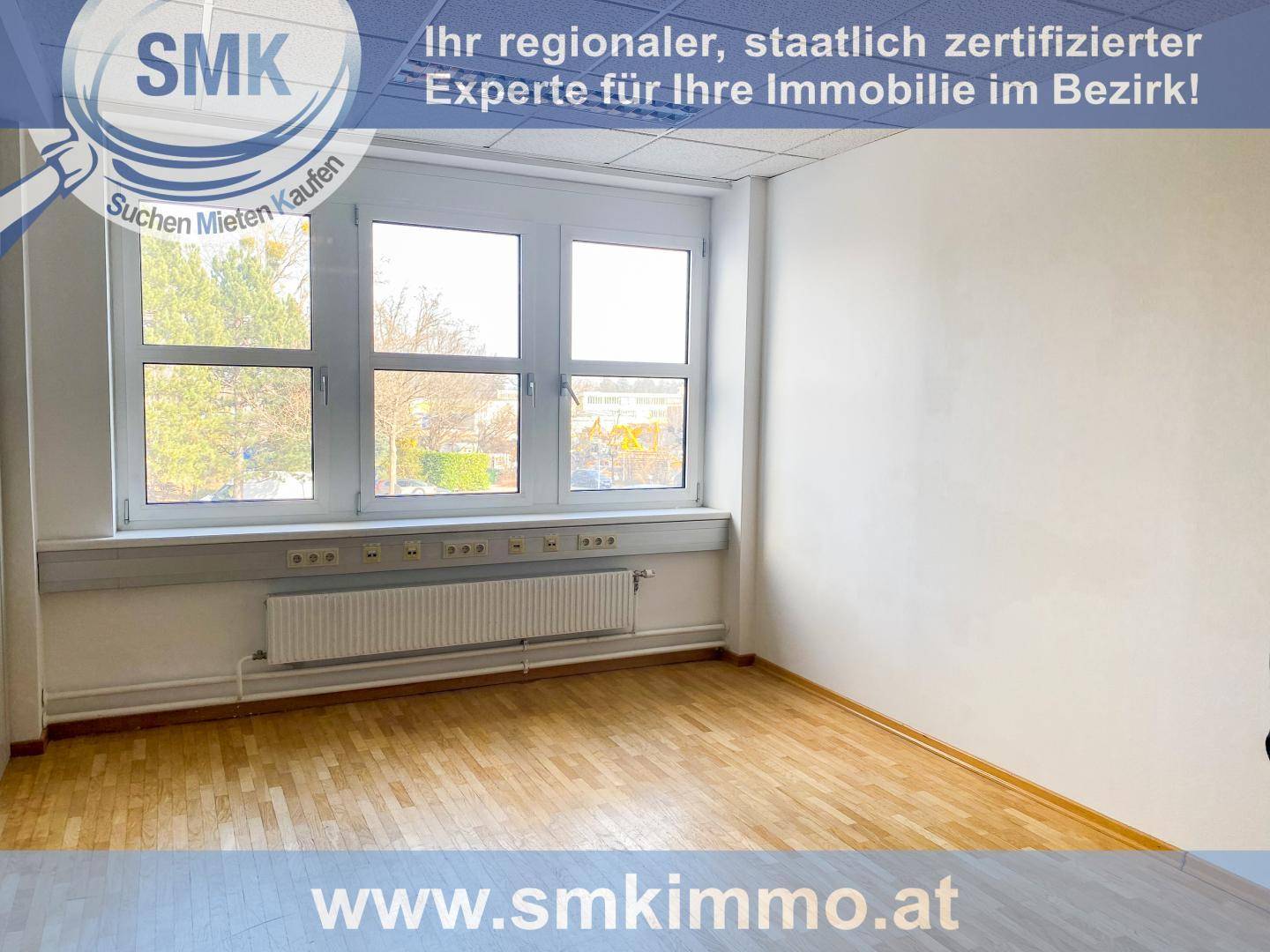 Leeres, helles Büro mit großen Fenstern, die viel Tageslicht hereinlassen, und einem warmen Holzfußboden.