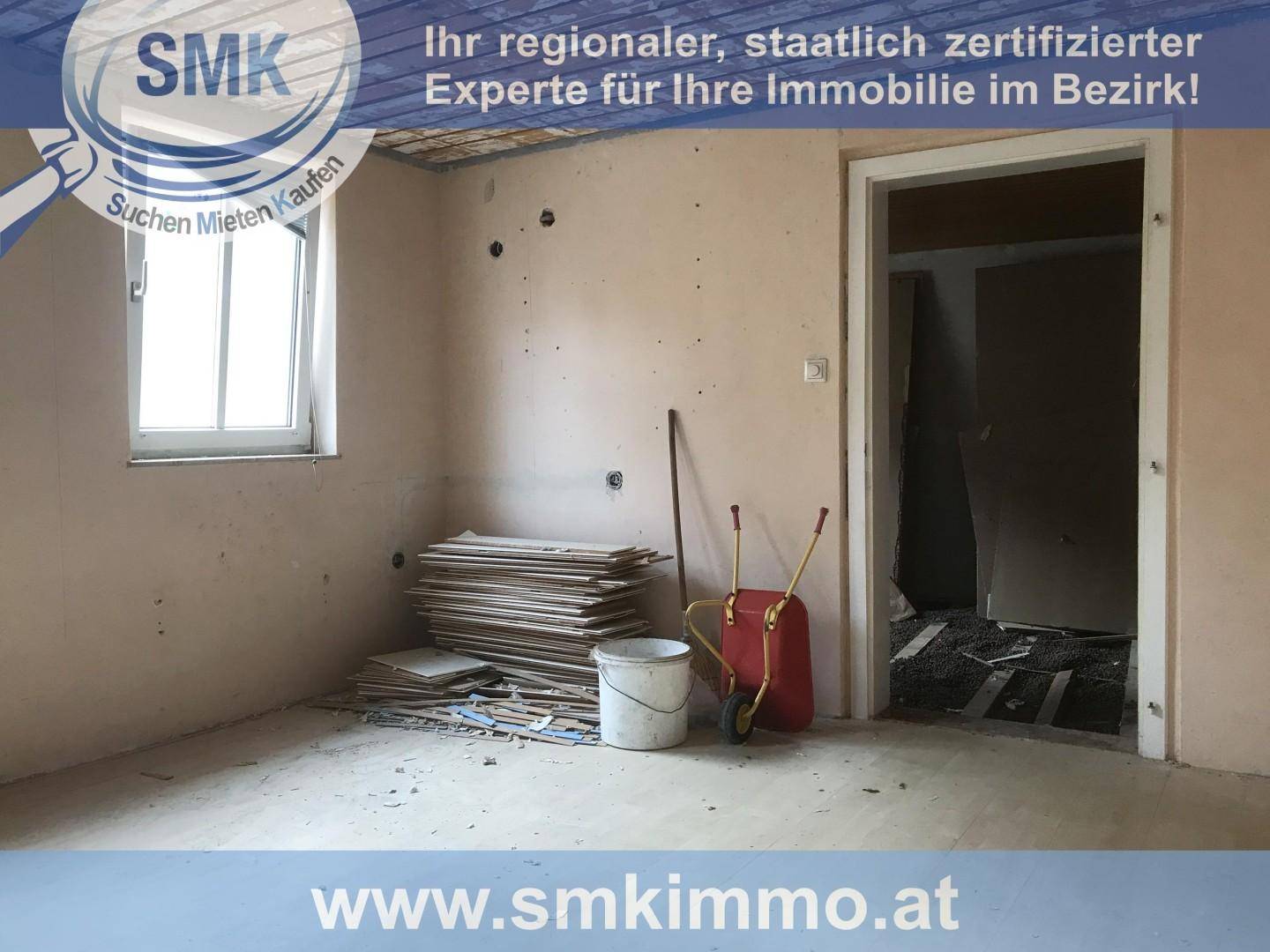 Renovierungsbedürftiger Raum mit Baumaterialien, kahlen Wänden und einem Fenster.