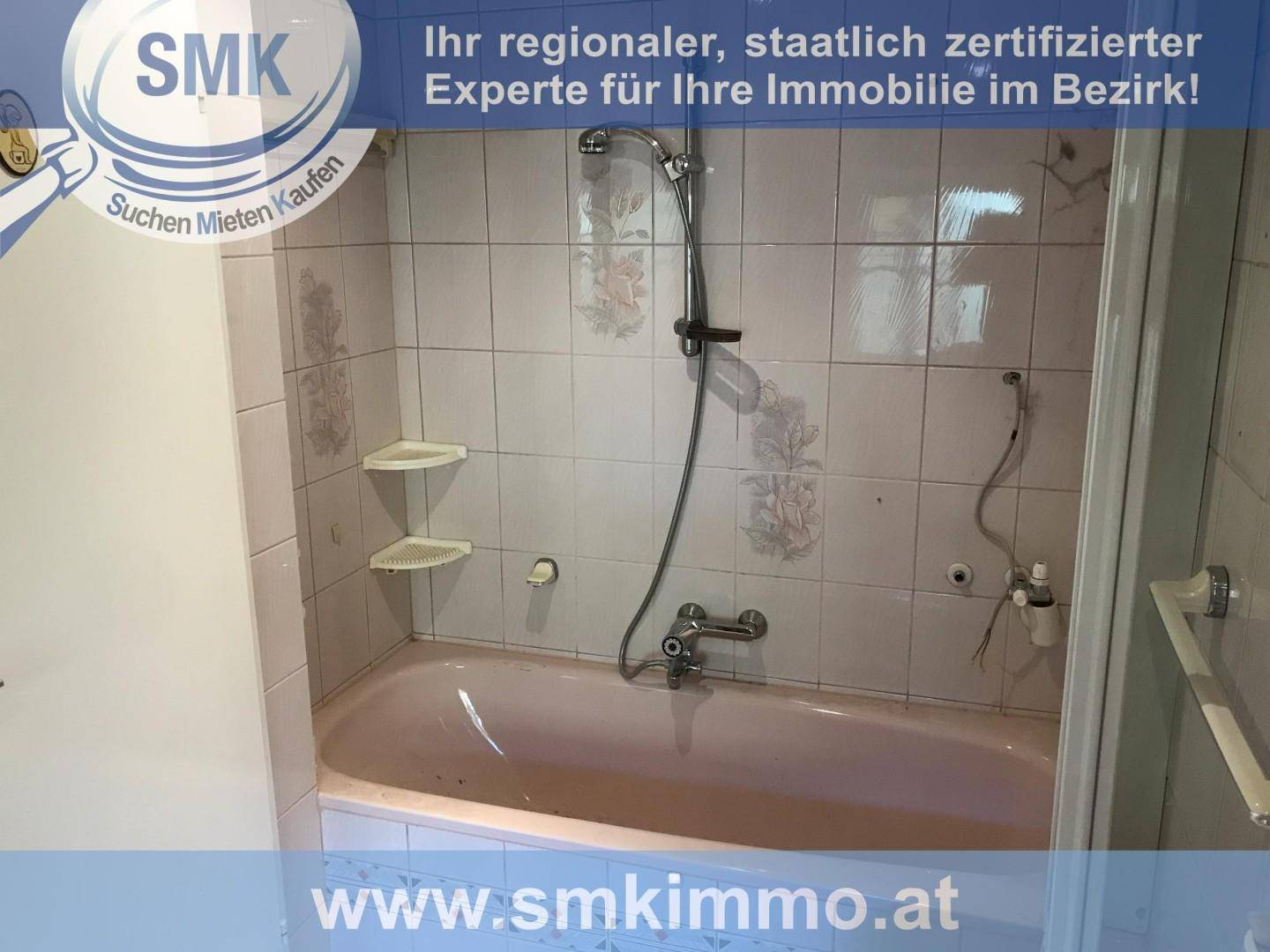 Badezimmer mit einer rosa Badewanne und hellrosa Fliesen mit floralem Muster.