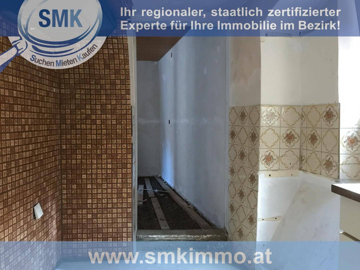 Küche im Renovierungszustand mit braunen Mosaikfliesen und floral gemusterten Wandfliesen.