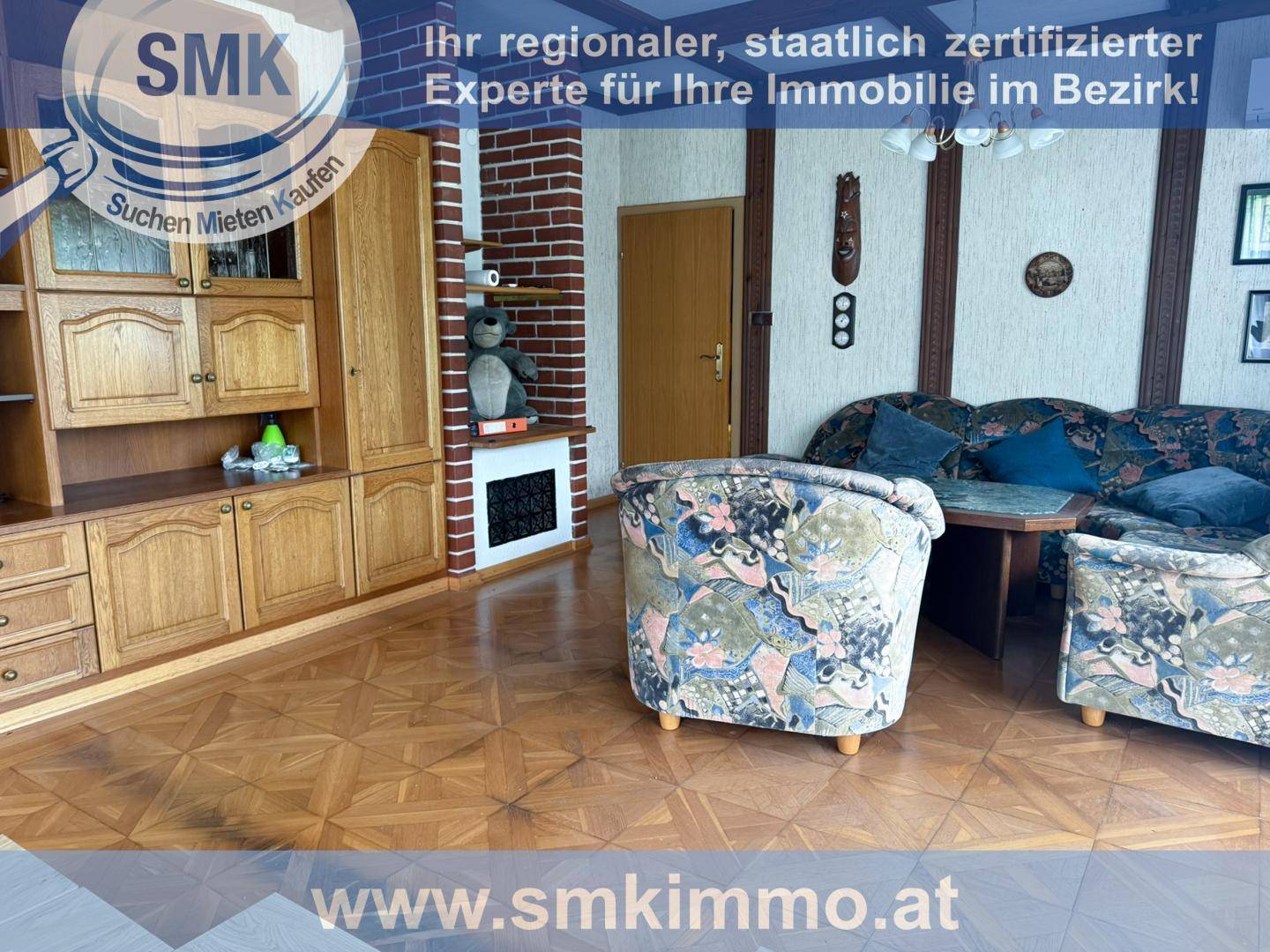 Gemütliches Wohnzimmer mit gemusterten Sesseln, Holzmöbeln und Parkettboden.
