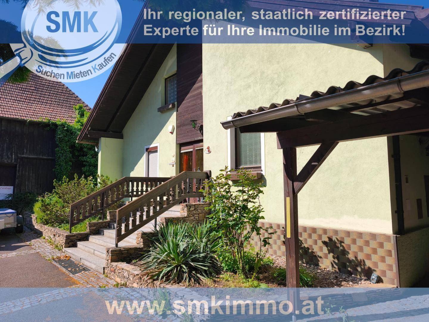 Vorderansicht des Hauses mit Eingangstreppe und einem überdachten Carport.