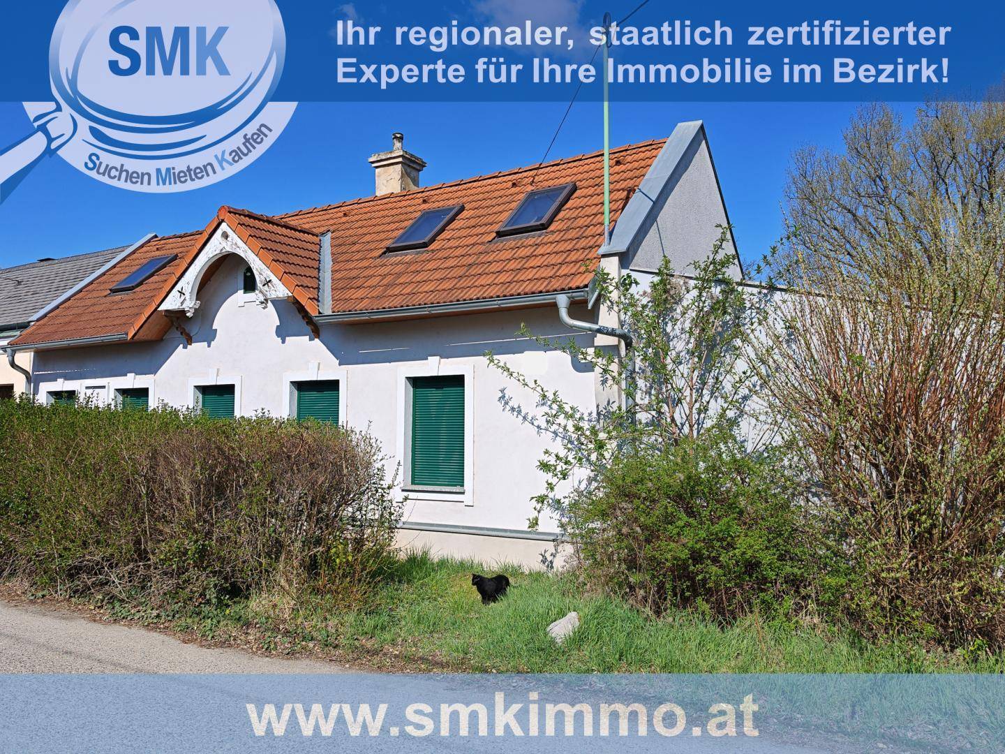 Einfamilienhaus mit rotem Ziegeldach und grünen Fensterläden in ländlicher Umgebung.