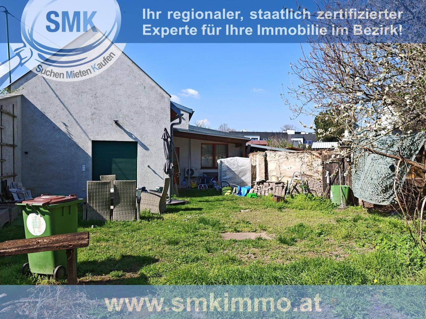 Hinterhof mit Rasenfläche, Gartenmöbeln und einem Schuppen in ländlicher Umgebung.