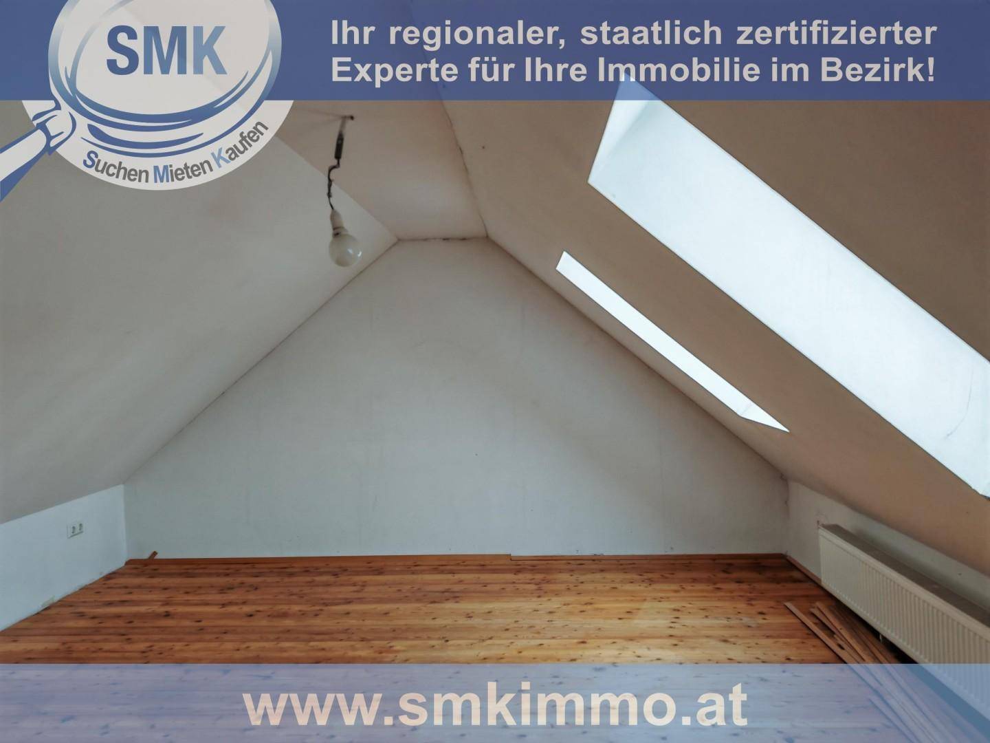 Heller Dachgeschossraum mit Holzboden, schrägen Wänden und zwei Dachfenstern für viel Licht.