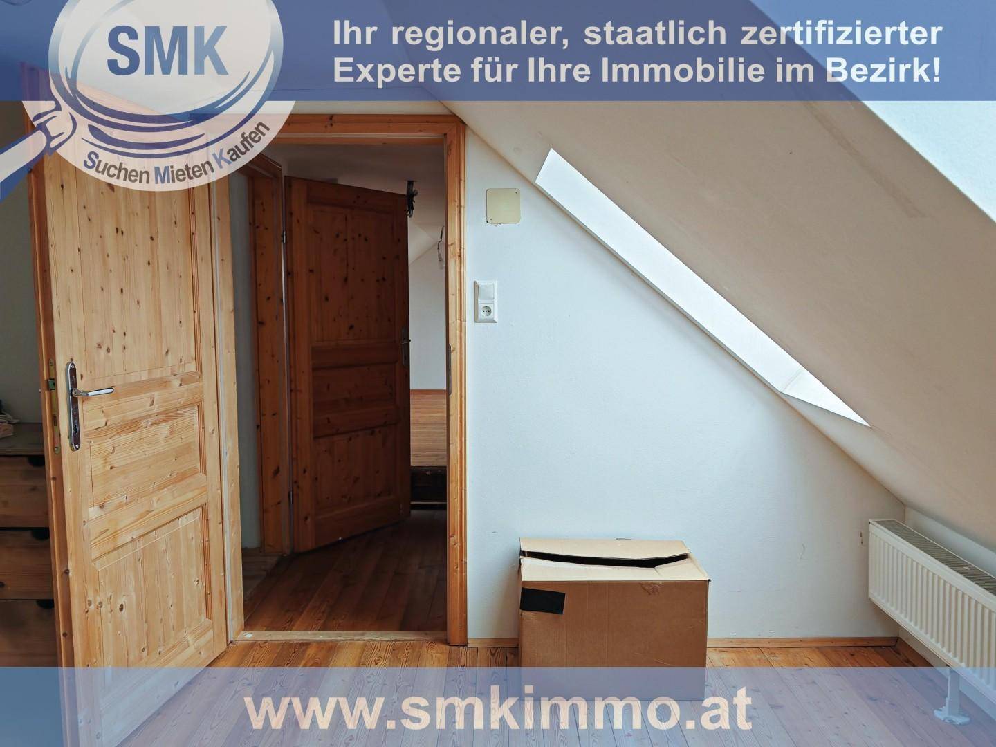 Dachgeschossraum mit schrägen Wänden, Holzboden und Dachfenster, das Tageslicht hereinlässt.