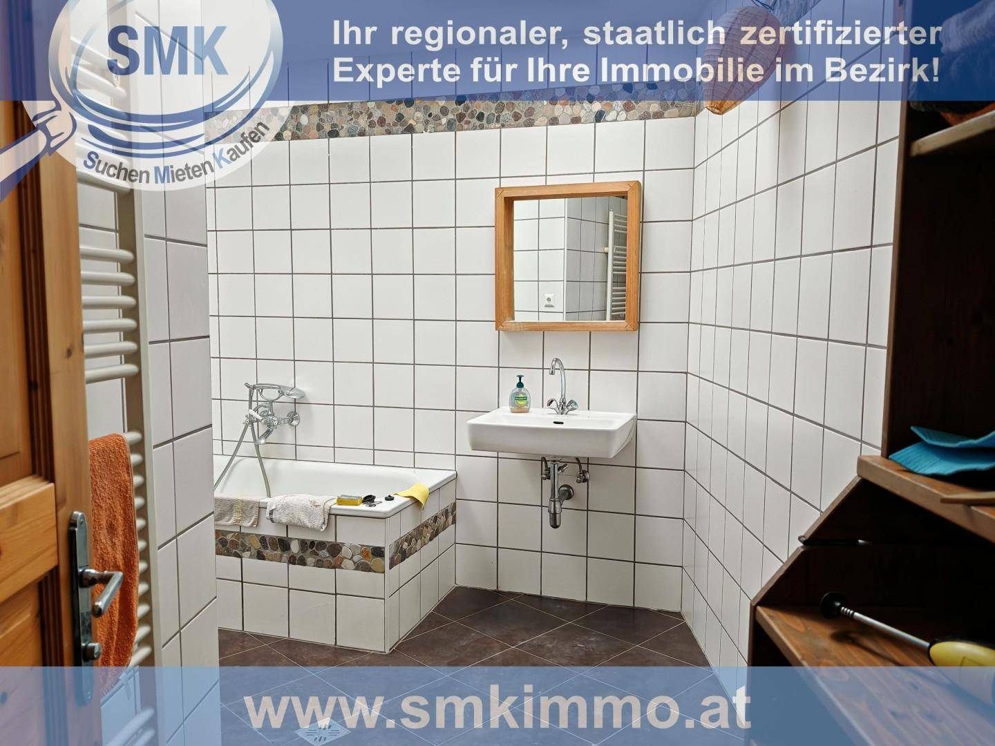 Badezimmer mit Badewanne, Waschbecken und weißen Wandfliesen in einfachem Design.