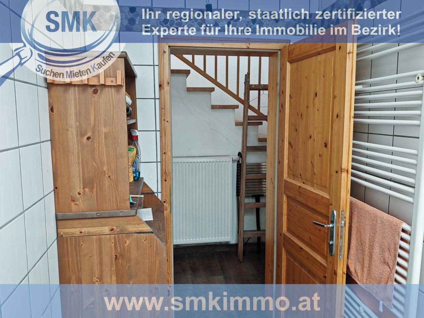 Kleines Badezimmer mit Waschbecken, Fliesen und Zugang zu einer Holztreppe.