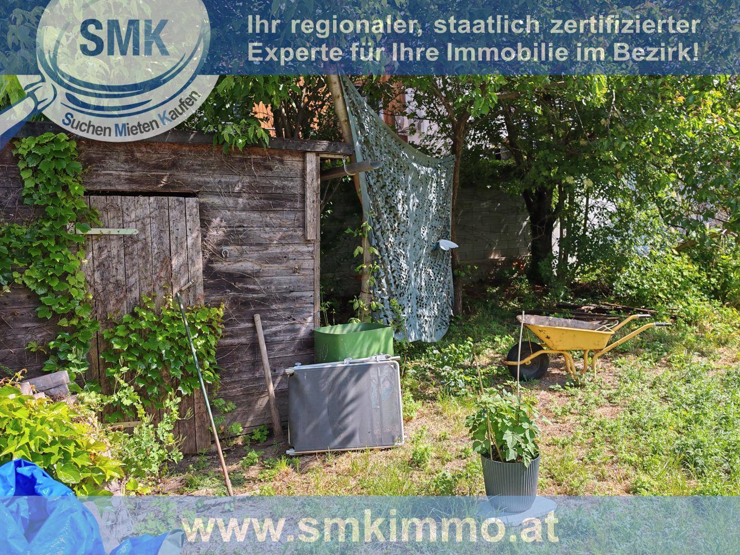 Rustikaler Holzschuppen in einem grünen Gartenbereich mit viel Vegetation und Geräten.