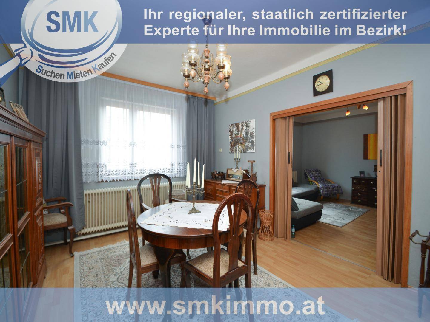 Klassisches Esszimmer mit rundem Holztisch, Stühlen und einem Kronleuchter.