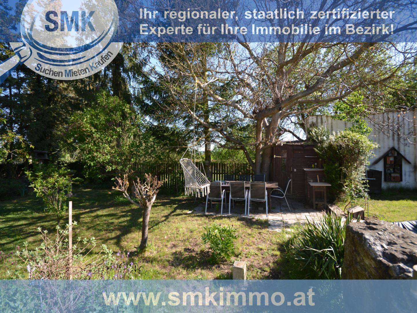 Gemütlicher Gartenbereich mit Esstisch unter einem Baum und Hängesessel.