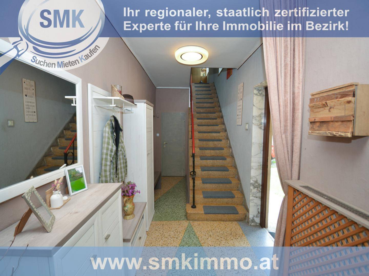 Heller Eingangsbereich mit Treppe, Spiegel und Garderobe in einem traditionellen Haus.