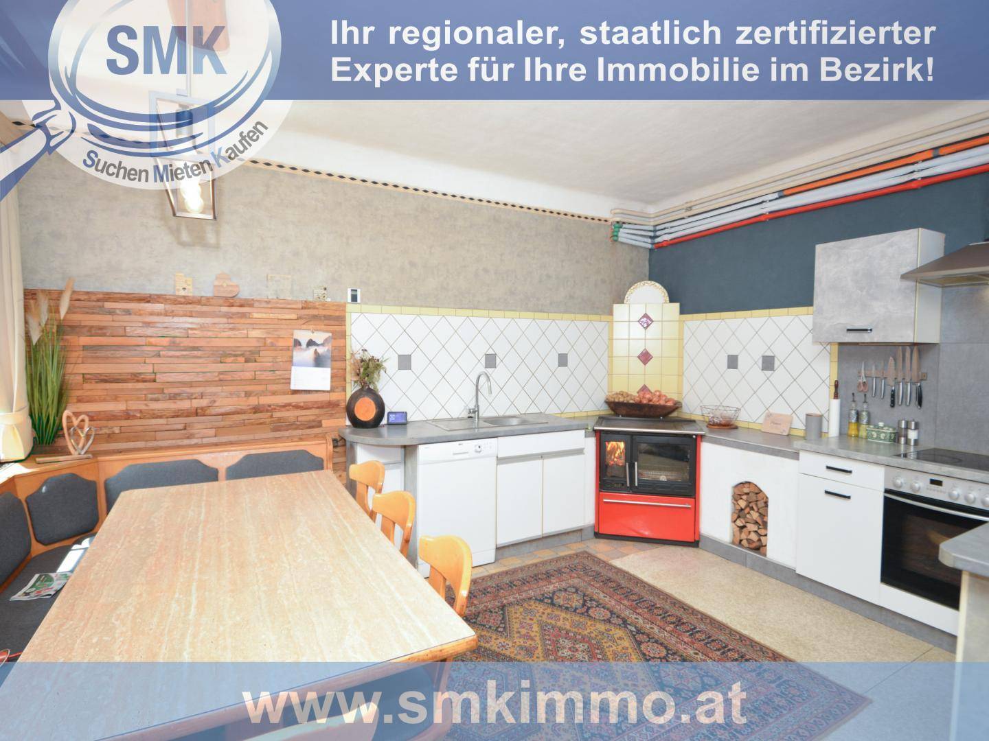 Rustikale Wohnküche mit Holztisch, Kachelofen und traditionellen Fliesen an der Wand.