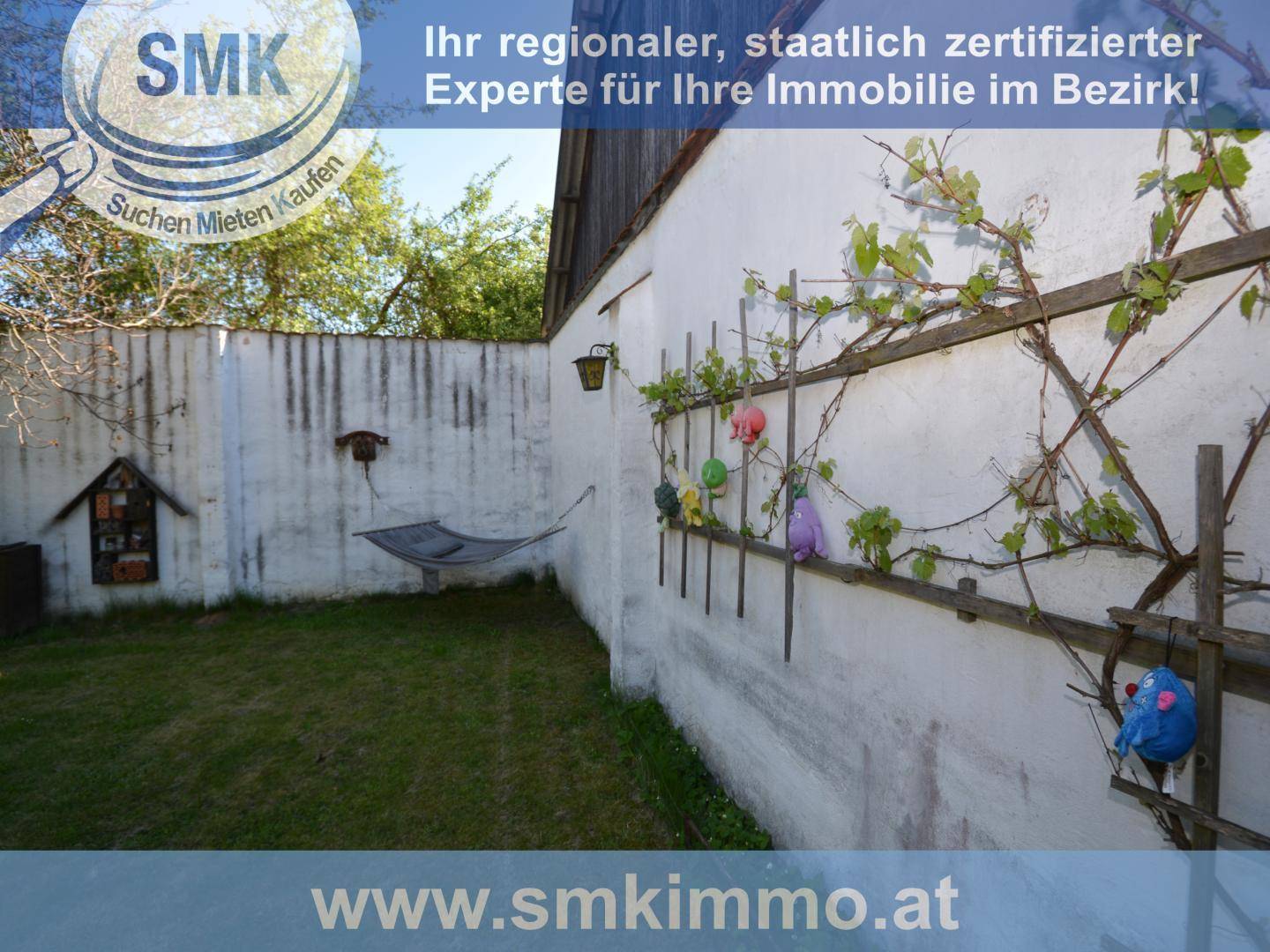 Kleiner, ummauerter Gartenbereich mit Hängematte und Rankpflanzen an der Wand.