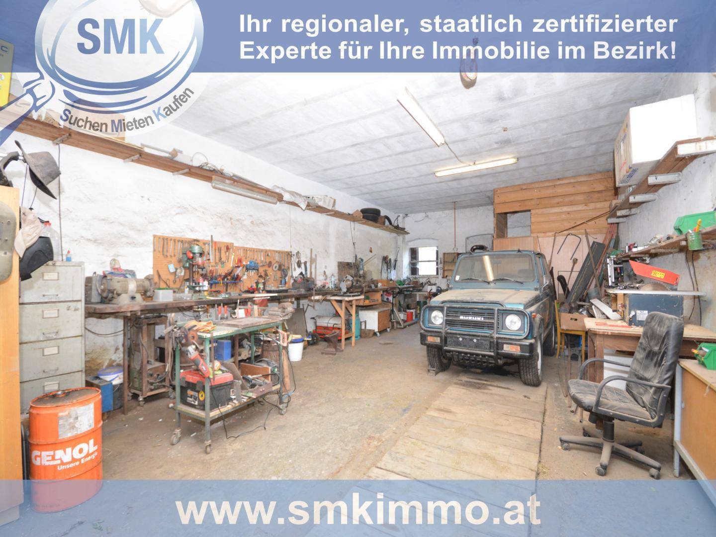 Große Werkstatt mit Arbeitsbänken, Werkzeugen und einem Fahrzeug.