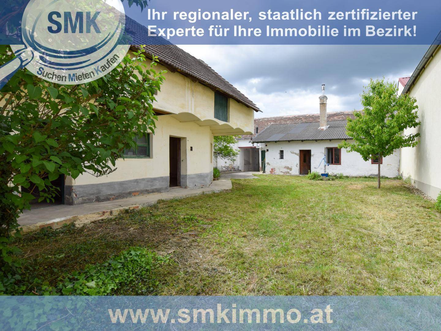 Großer Gartenbereich mit Rasenfläche und älteren Gebäuden im Hintergrund unter bewölktem Himmel.