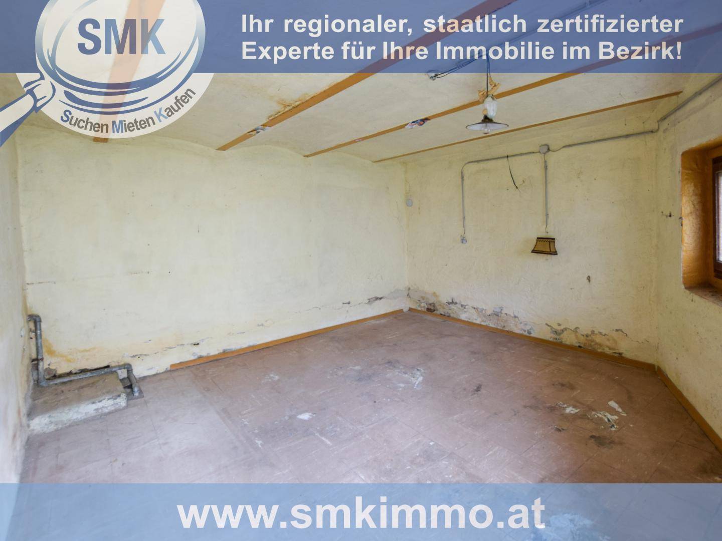 Leerer Abstellraum mit gelblichen Wänden, sichtbaren Balken und Betonboden in einfachem Zustand.